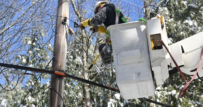 Lineworker in bucket working on wires attached to utility pole