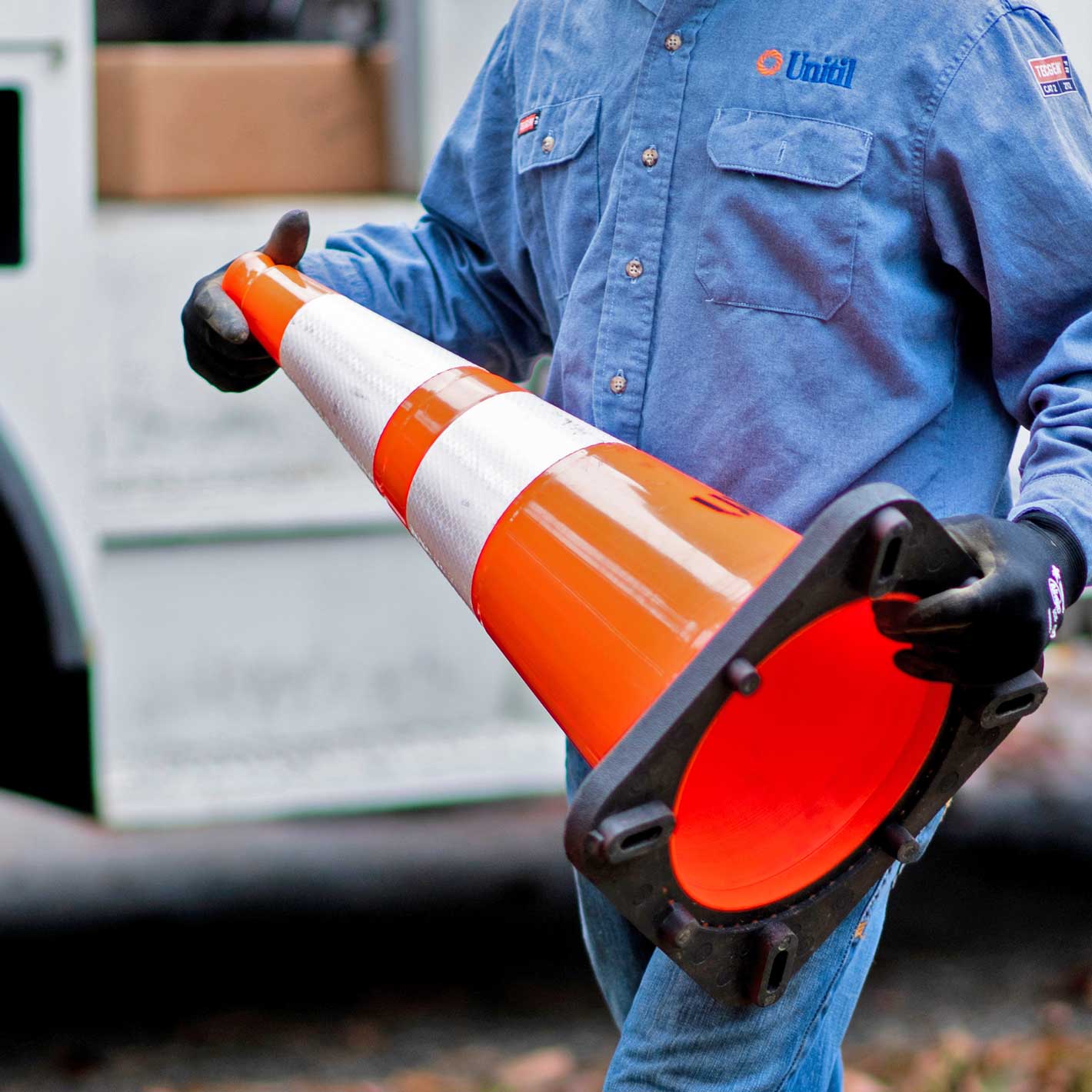 A Unitil employee placing a safety cone at a work site.