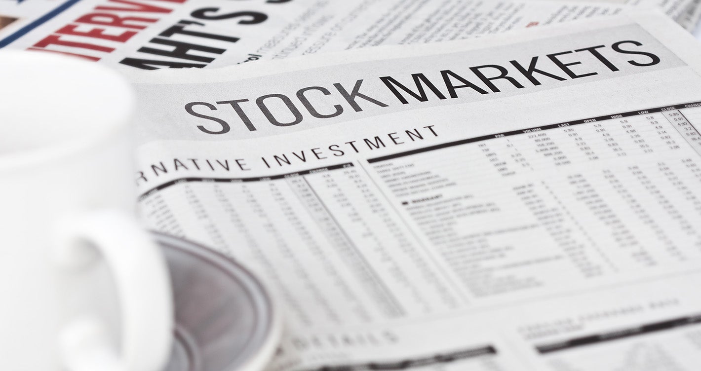 cup of coffee placed on stock market section of newspaper