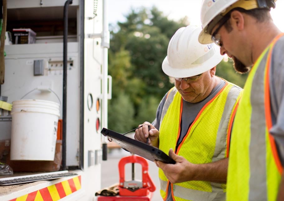 Unitil workers behind truck working on ipad
