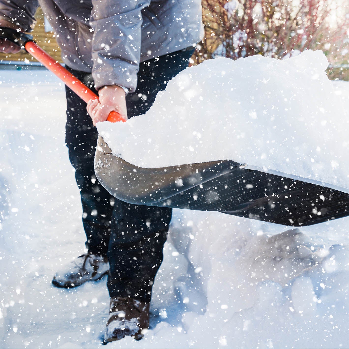 person shoveling snow with orange handle show shovel