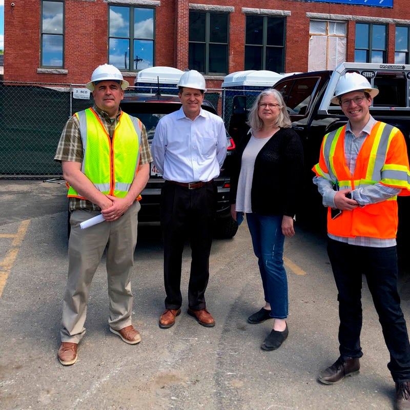 workers pose on street in front of Moran Square building construction