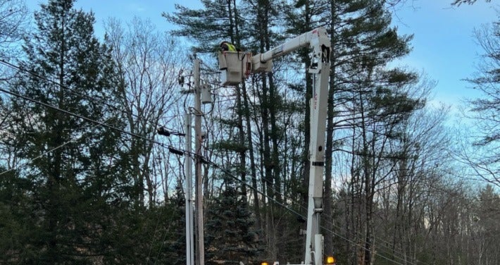 Lineman in bucket truck with arm extended. 