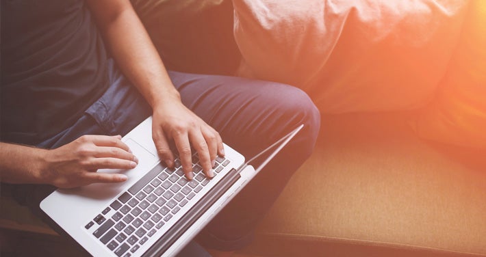 person sitting on couch with laptop computer and sun glare coming through window