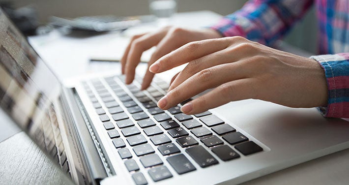 closeup of hands typing on laptop computer
