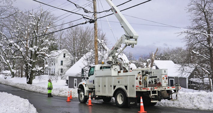 Unitil bucket truck with worker fixing powerline on snowy street