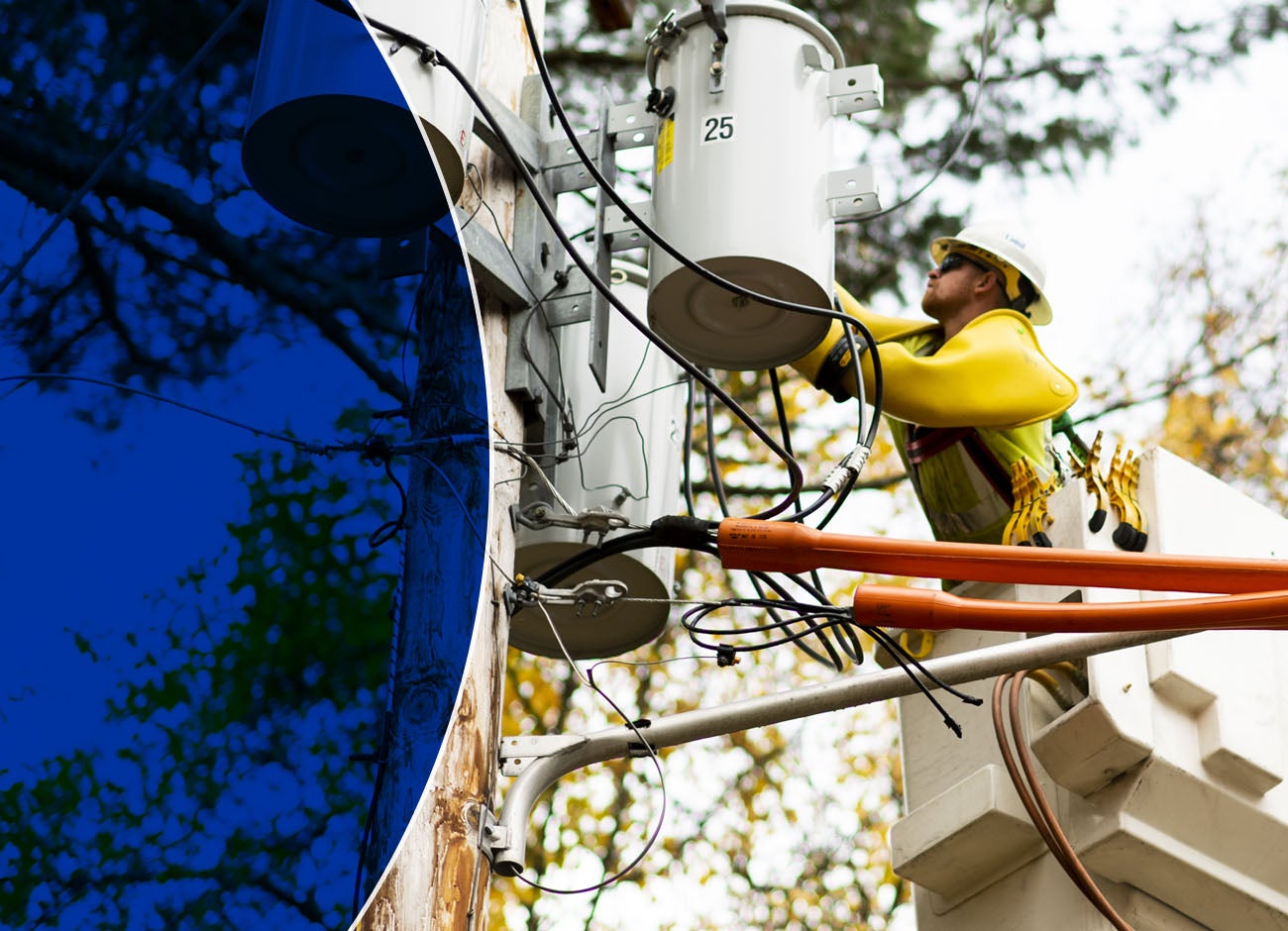 utility worker in bucket lift with wires in foreground and tress in background