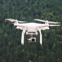 drone flying against tree backdrop