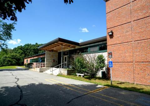 brick exterior of Ashby school main entrance with stairs and trees
