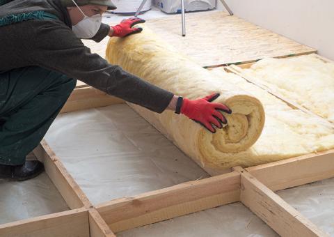 person wearing gloves rolling out insulation