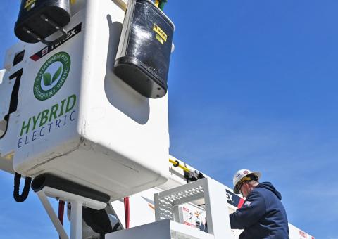 closeup of bucket arm with hybrid electric graphics and Unitil worker