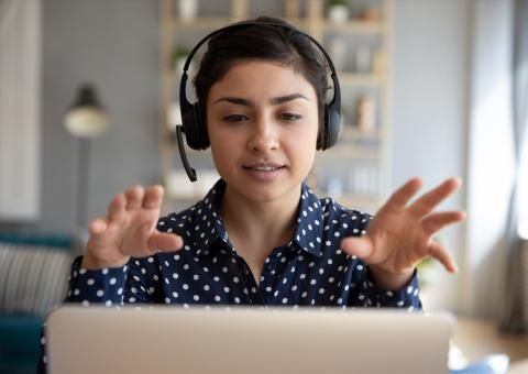 customer service representative with headphones sitting behind laptop