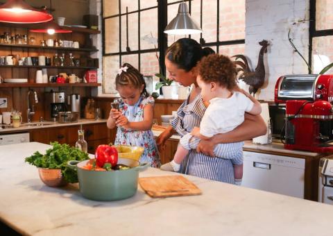 A little girl preparing food with her mother in a kitchen