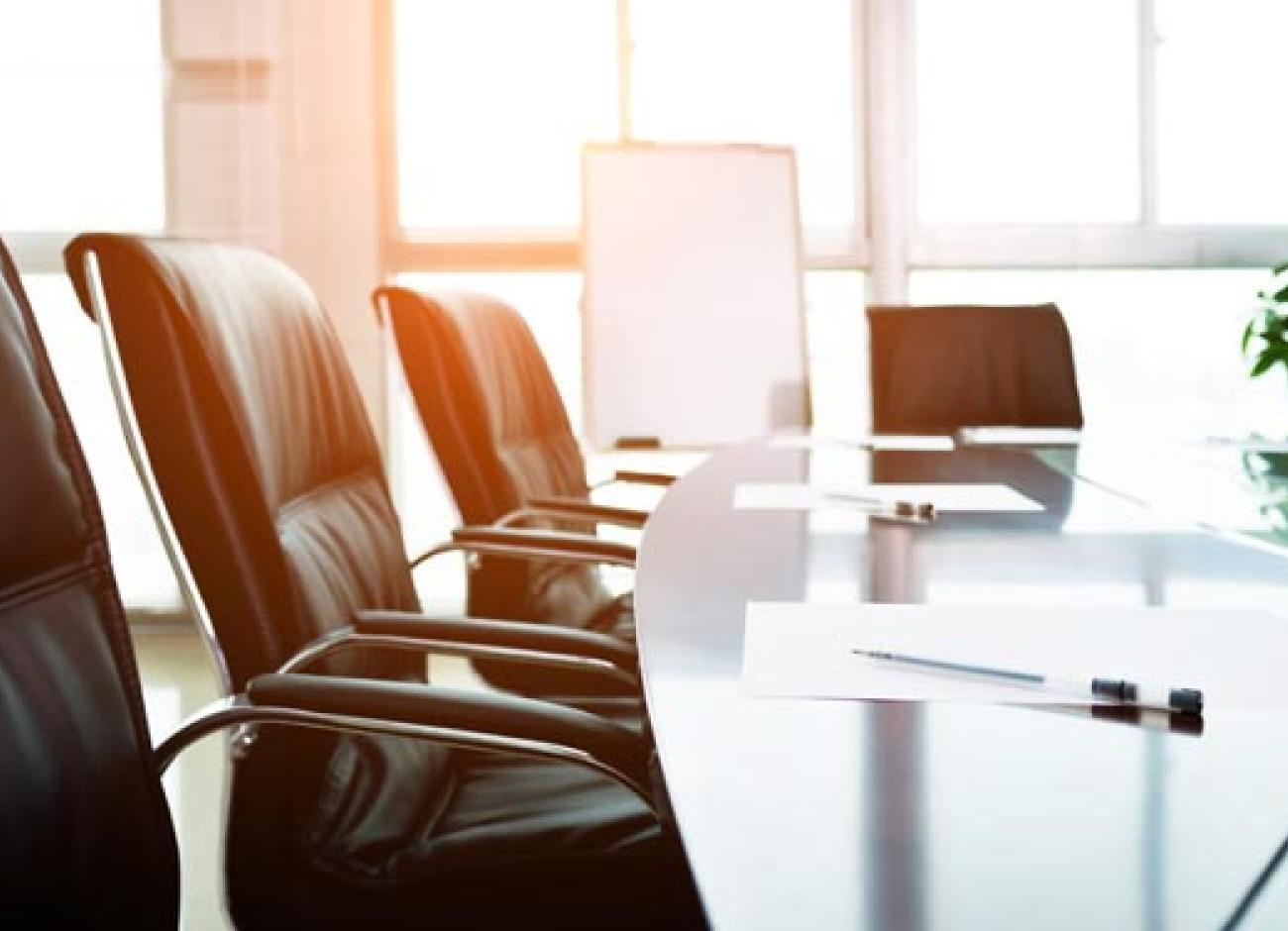 empty seats at a board room table with sun shining in