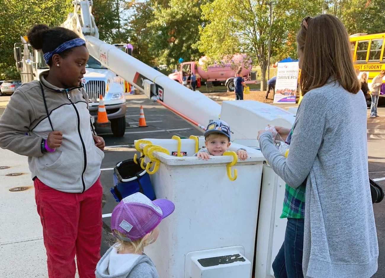 toddler in bucket of a bucket truck as three younger kids look on